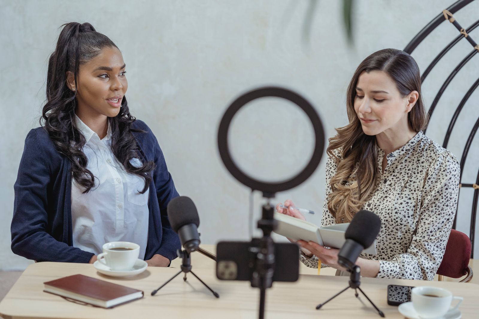Sala de estúdio com sofá estofado e dois microfones articulados posicionados para gravação de podcast