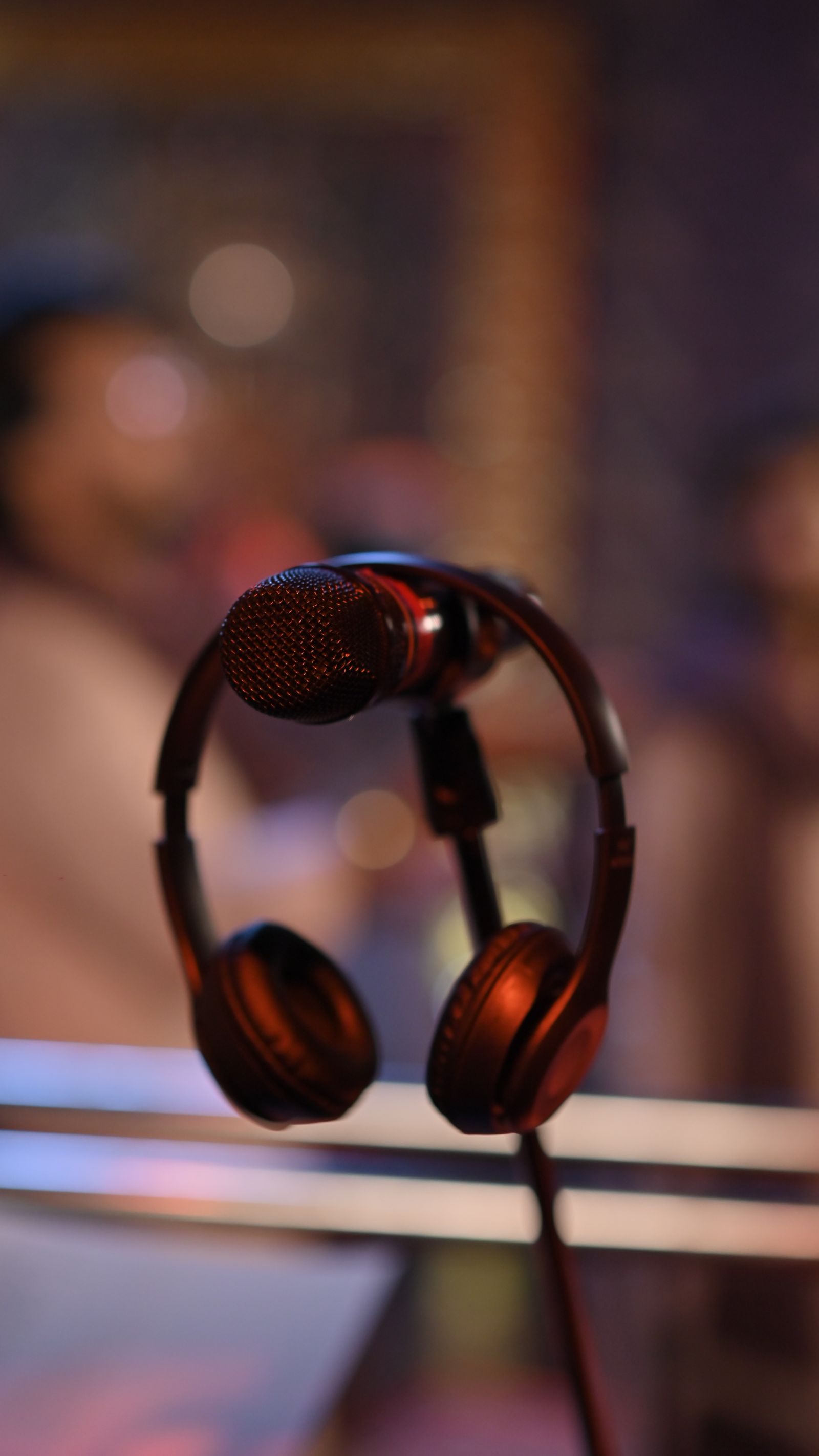 Microfone de estúdio ao lado de equipamento de gravação audiovisual sobre mesa de trabalho